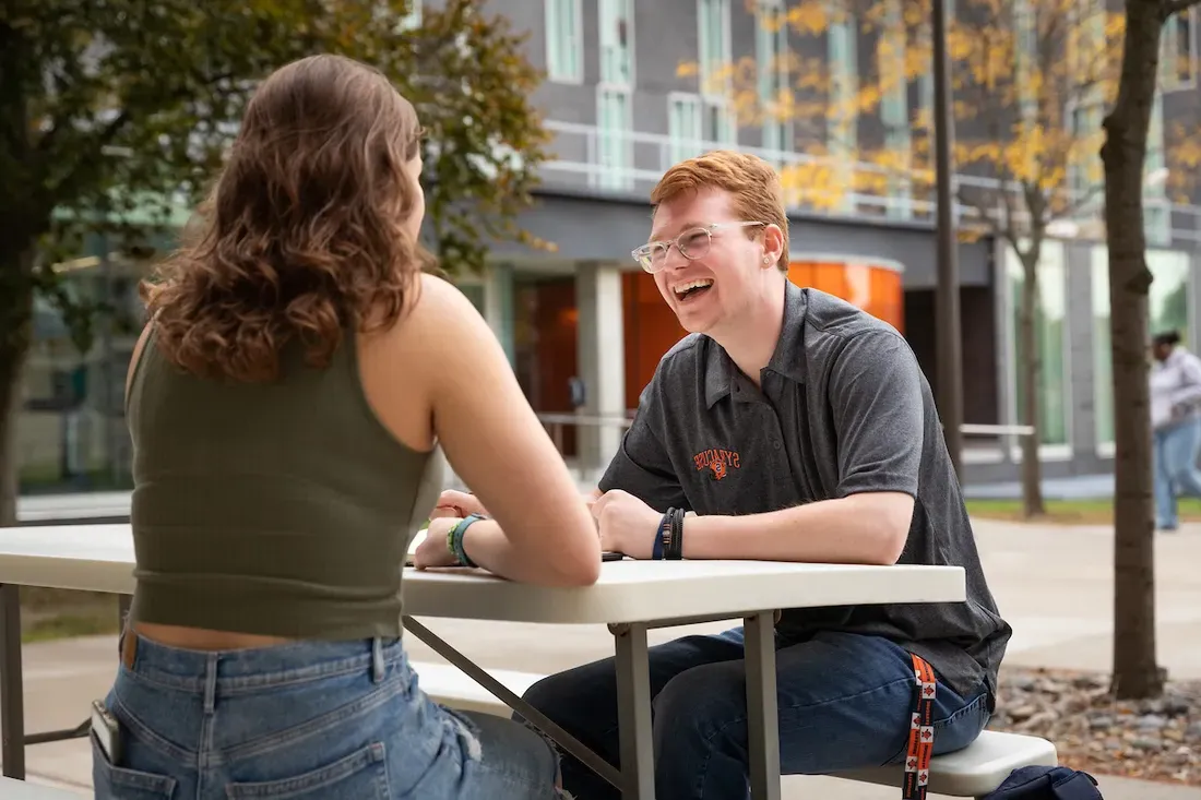 Two students sitting at a picnic table.